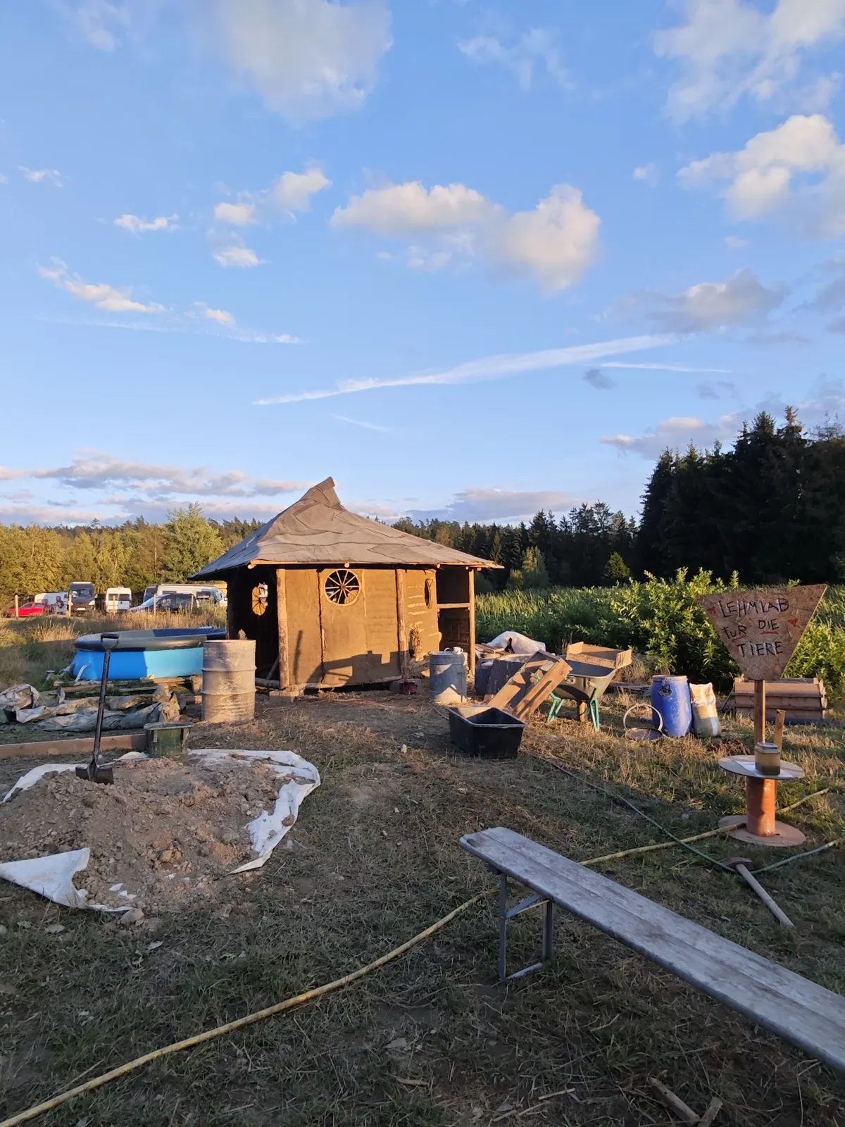 Die Lehmhütte im Abendlicht mit dem Schild „Lehmlab für die Tiere“