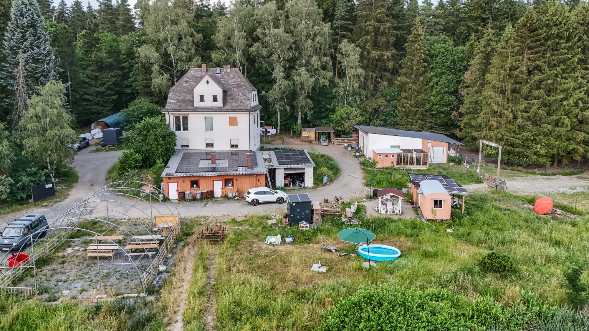 Der Hof aus der Luft, umgeben von Wald