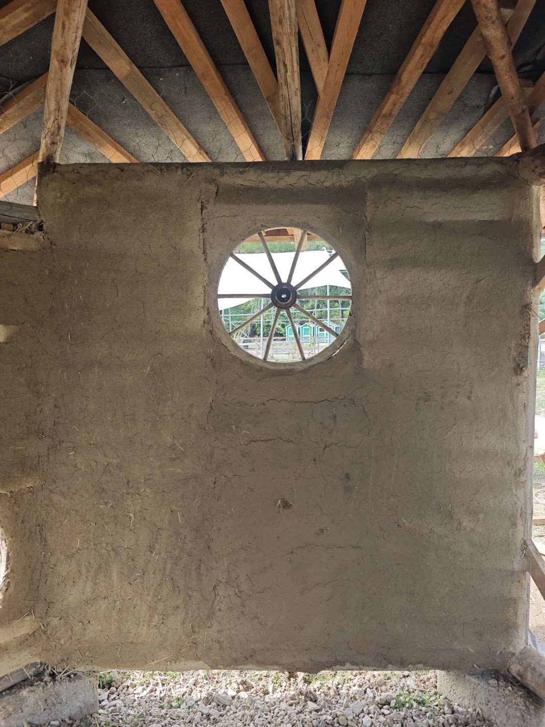 Lehmwand mit rundem Wagenrad-Fenster